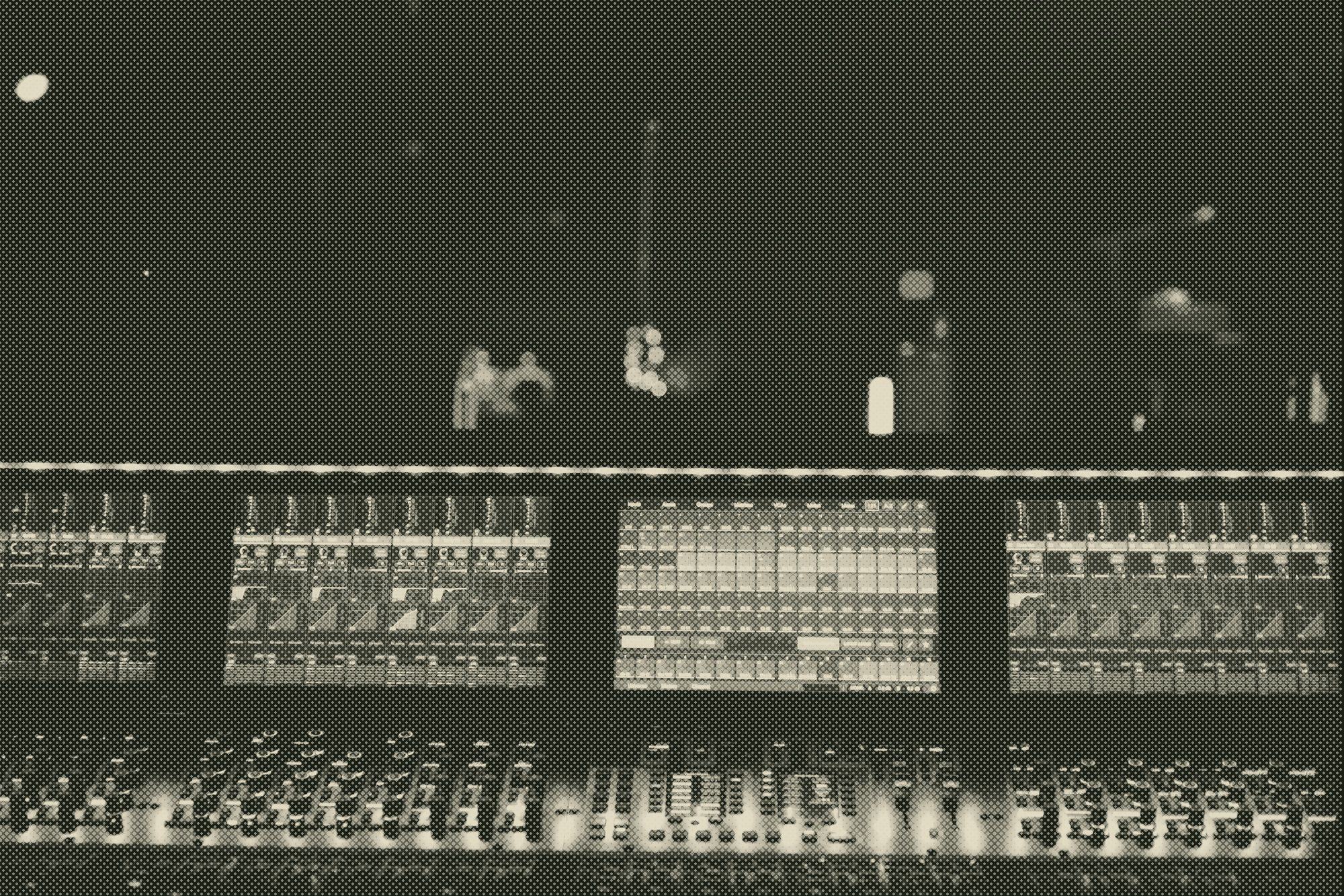 a mixing console lit softly in a dark room