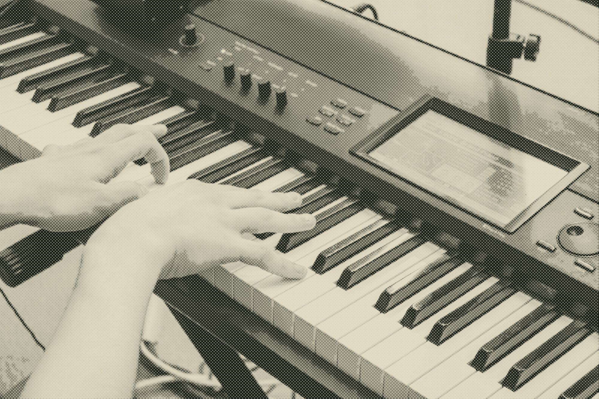 hands playing a digital piano in low light