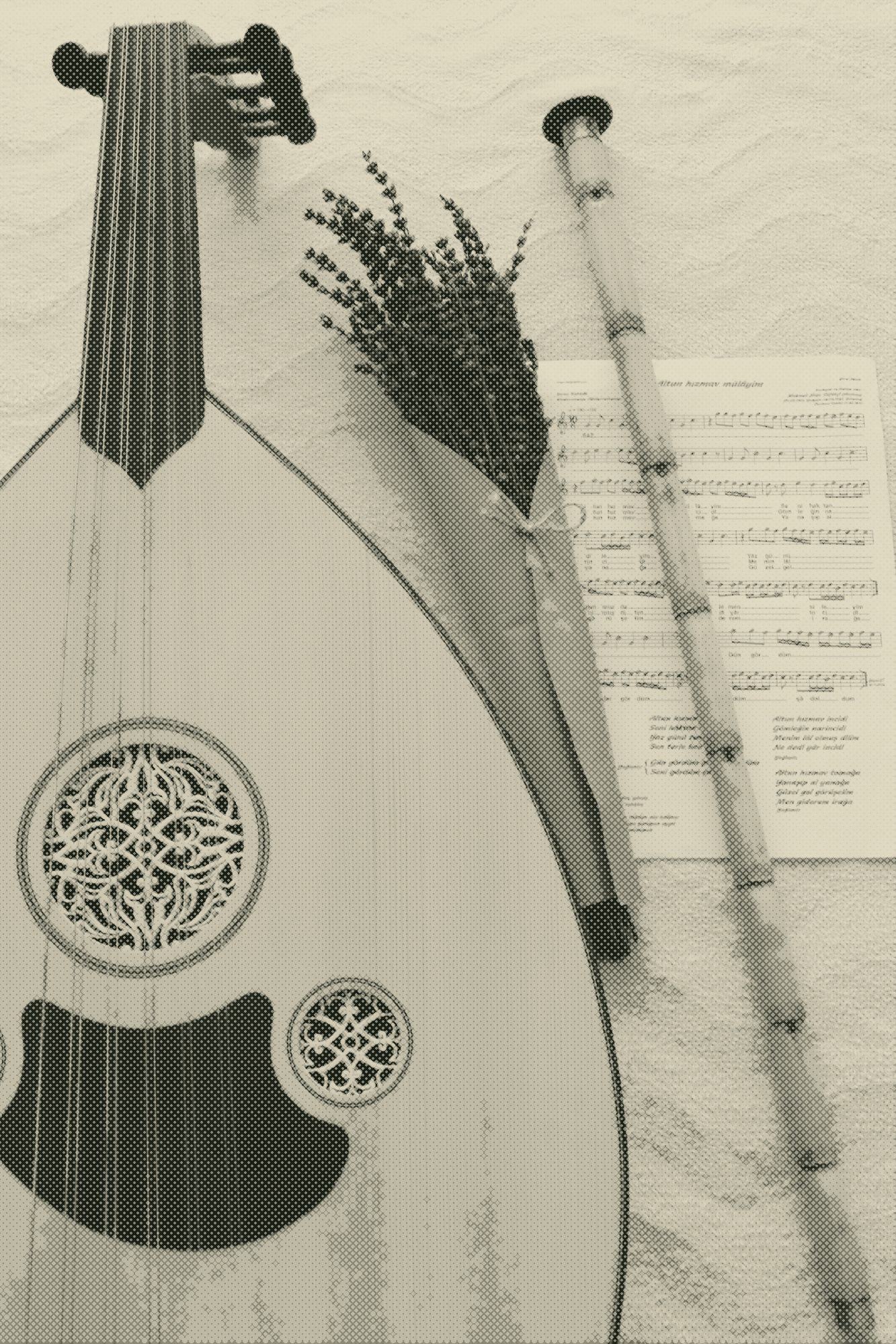 an oud and a ney resting among sheet music and dried lavender