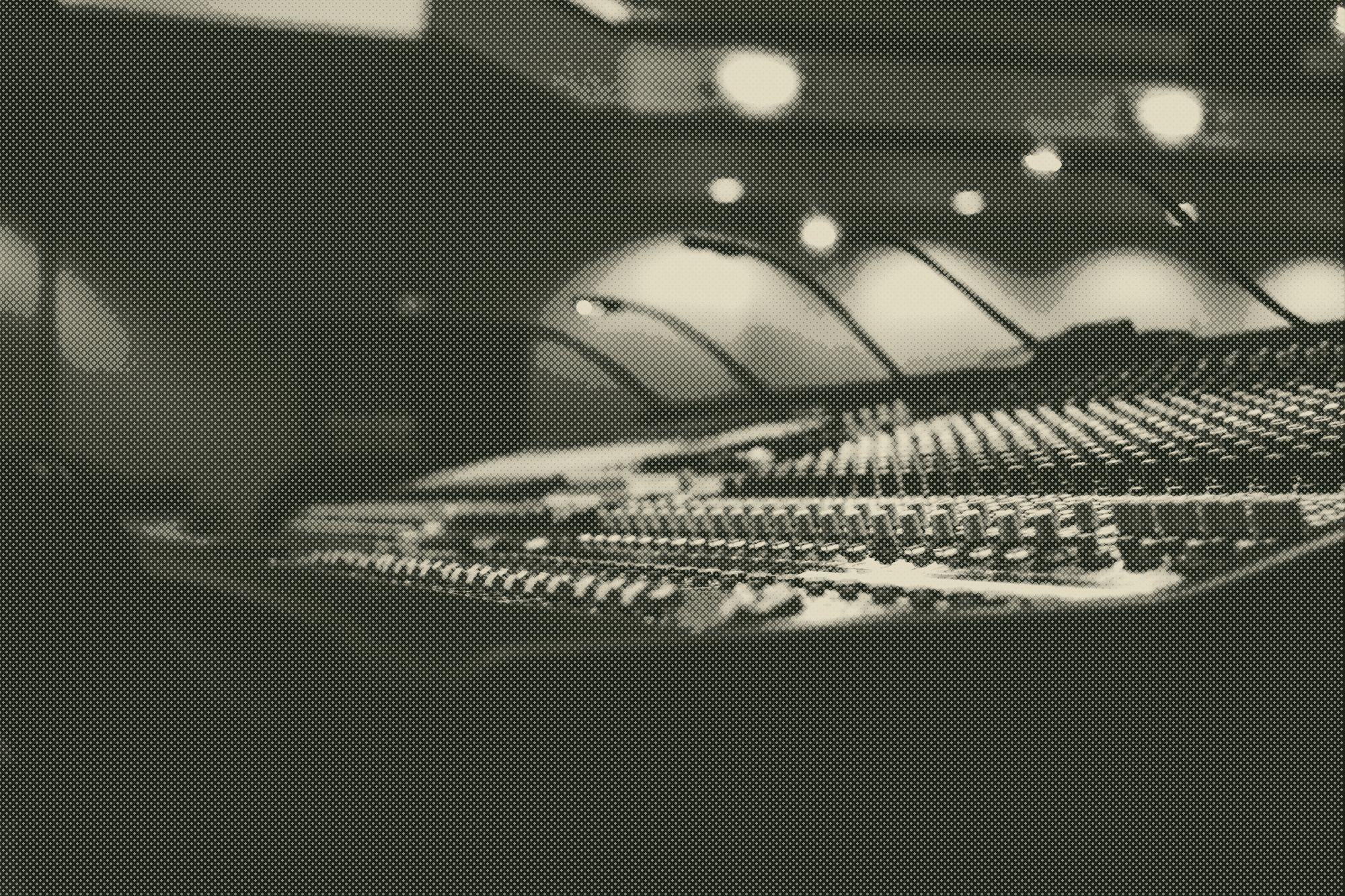 a studio mixing console in low, warm light